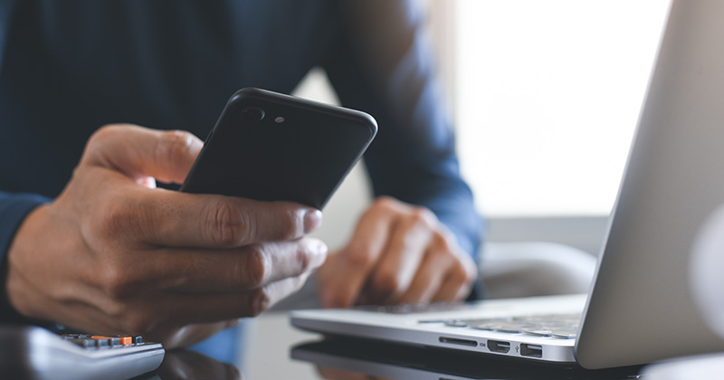 Locksmith Scrolling on Phone Looking at Field Service Management Software