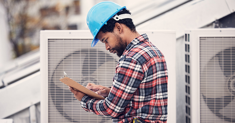 Male HVAC employee looking at clipboard on the job