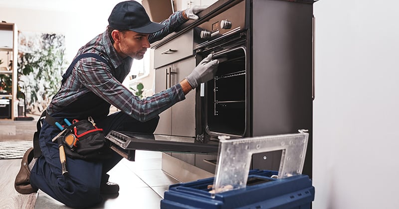 Appliance repair worker fixing oven