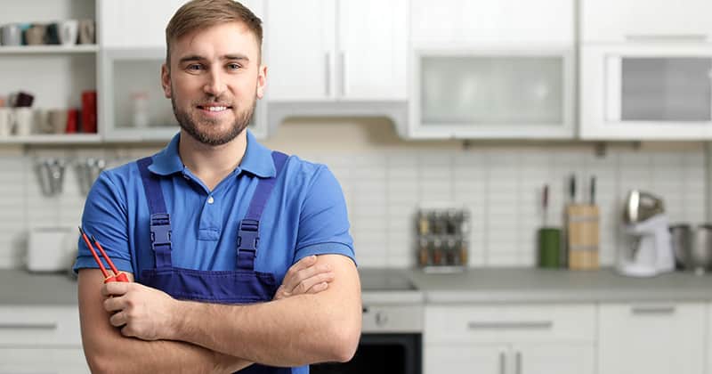 Repair man smiling in kitchen