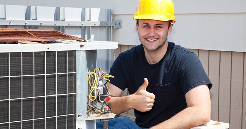HVAC professional smiling and holding thumbs up