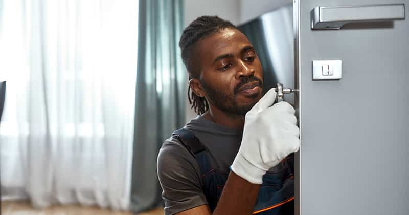 Young locksmith working on door