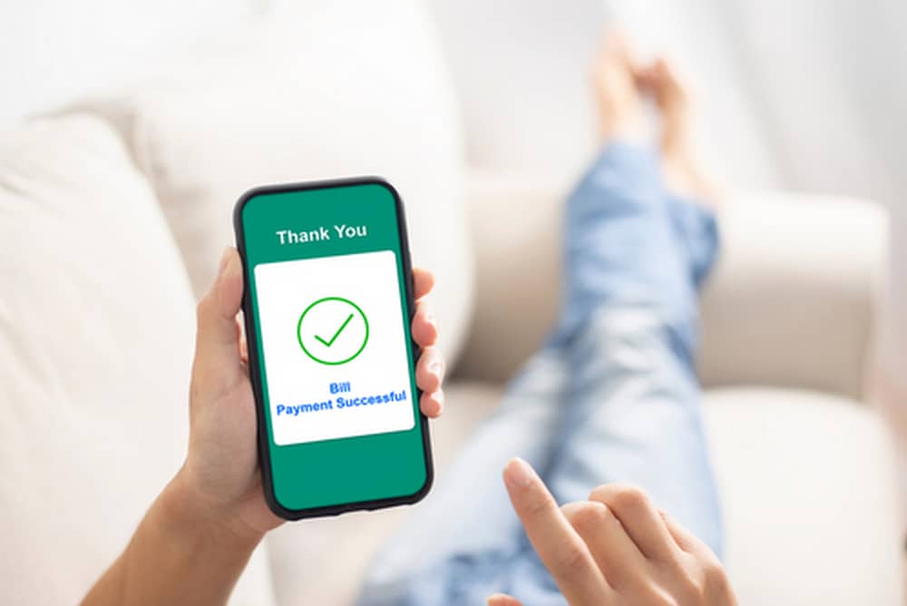 a person using a smartphone to complete an online bill payment at home
