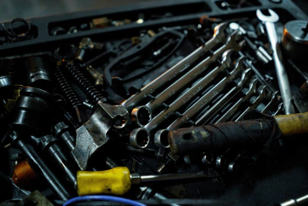 Close-up of a tool kit with wrenches, a hammer, and other mechanical tools scattered in a box.