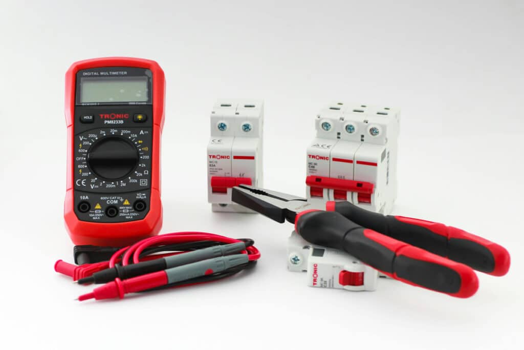 Electrical tools and components are arranged on a table representing study materials for an electrician certification.