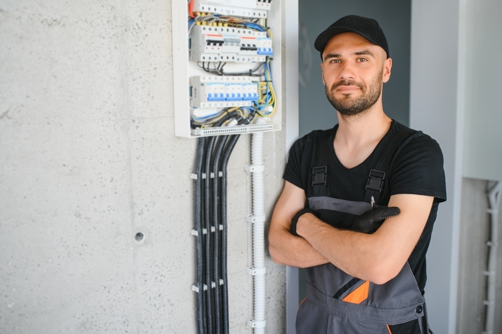 Electrician standing next to an open electrical switchboard with fuses