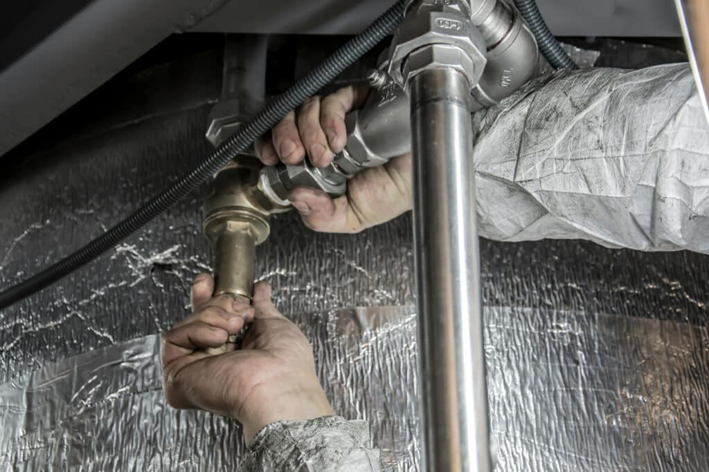 A plumber connecting metal pipes as part of basic plumbing work and skills training.