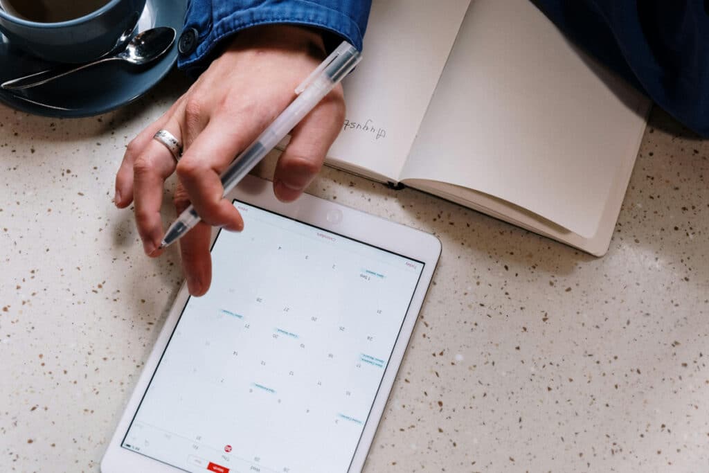 Person using a tablet to manage scheduling, planning tasks, and organizing appointments on calendar.