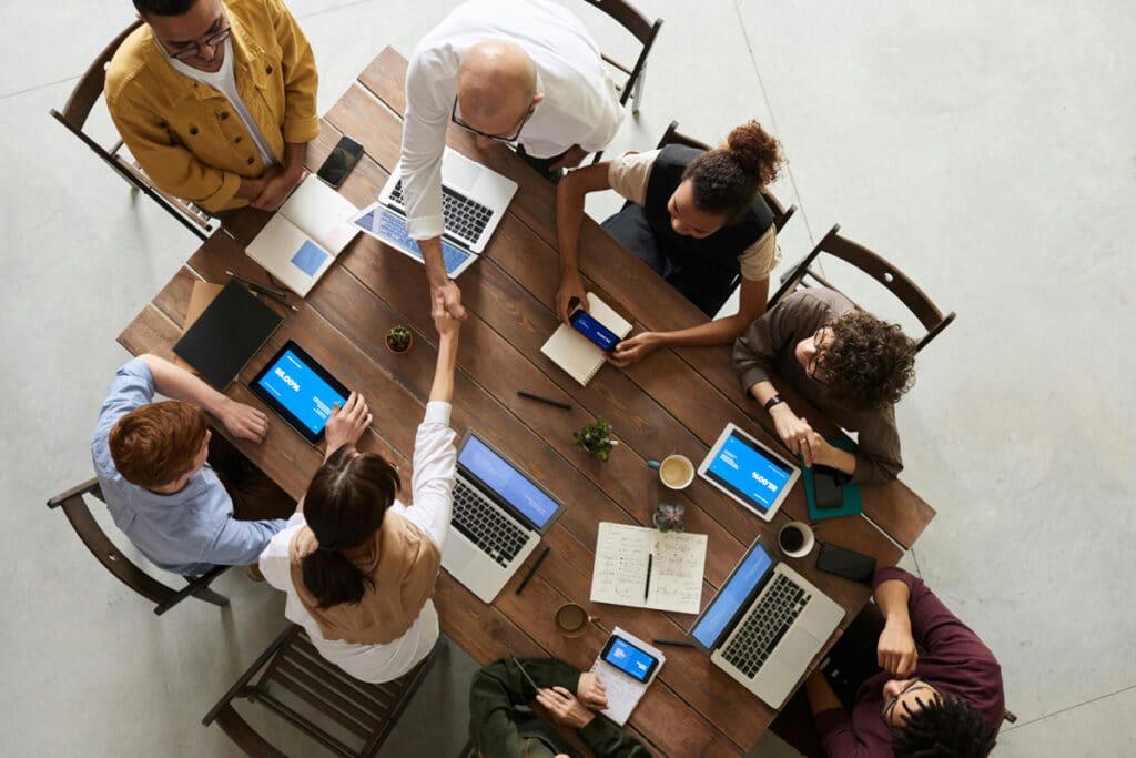 Team of professionals collaborating in a meeting with laptops, discussing field workforce management software.